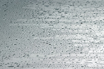 Water drops on grey glass surface, closeup