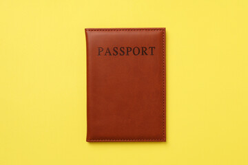 Passport in leather cover on yellow background, top view