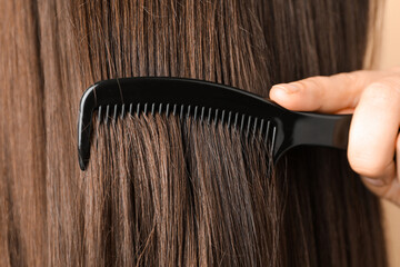Obraz premium Woman brushing hair with plastic comb, closeup