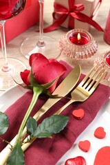 Romantic place setting with red rose on white table, closeup. Valentine's day celebration