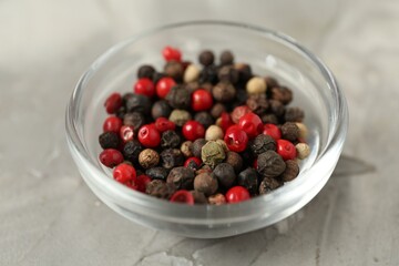 Bowl of peppercorns on grey textured table, closeup