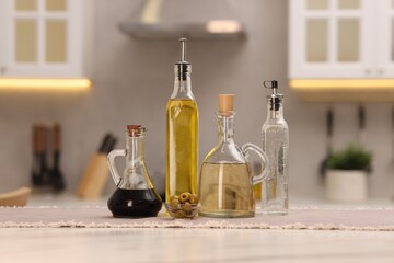 Bottles of salad dressings and olives on white table in kitchen