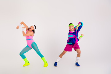 Energetic couple in vibrant retro fitness outfits showcasing dynamic movements against a minimalist white background