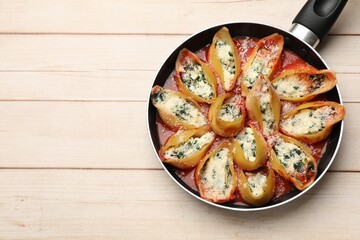 Delicious shell pasta stuffed with ricotta and spinach on white wooden table, top view. Space for text