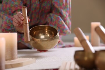 Woman with singing bowls and burning candles indoors, closeup