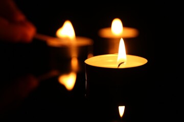 Burning candles on surface in darkness, closeup