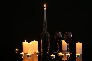 Many burning candles on mirror surface against black background