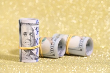 Many dollar banknotes on golden glitter background, closeup