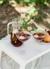 Refreshing cocktail served outdoors with a floral centerpiece in a serene garden setting on a sunny day