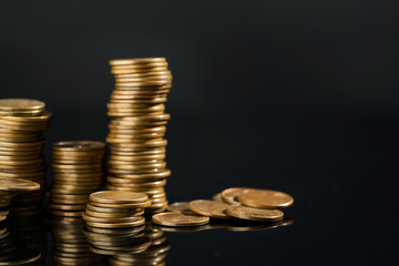 Many stacked coins on dark mirror surface, closeup. Space for text