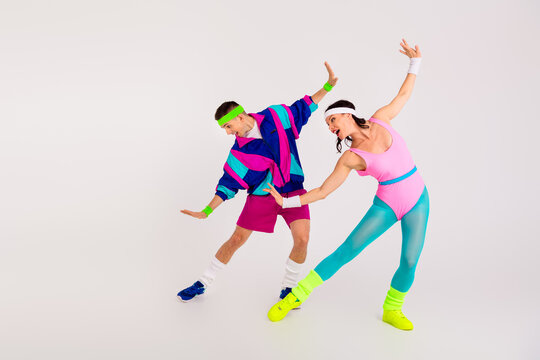 Colorful retro aerobics dance duo energetically exercising on a white background, dressed in vibrant 80s activewear, headbands