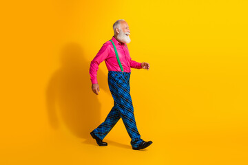 Full length photo of fashionable old gentleman walking step wear glamour garment suspenders isolated bright yellow color background