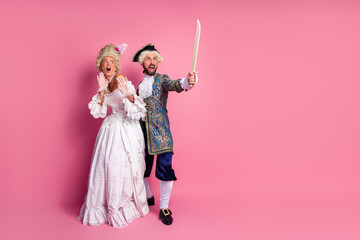 Elegant couple in vintage noble costumes posing against a pink backdrop