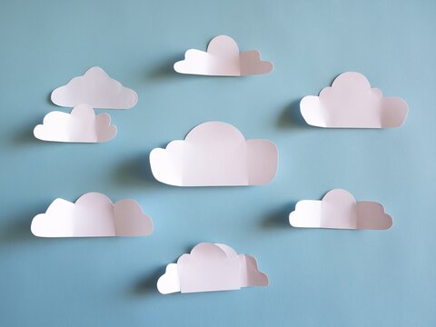 Abstract arrangement of white paper clouds against a light blue background for a whimsical look.