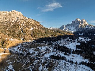 Fototapeta premium Panoramic view of the Dolomites mountains in winter, Italy. Santa Fosca Civetta resort.Ski resort in Dolomites, Alps in Italy. Aerial drone view of Santa Fosca ski slopes and mountains in dolomites.