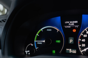 Closeup of hybrid car dashboard displaying Power, Charge, Eco modes. The illuminated indicators...