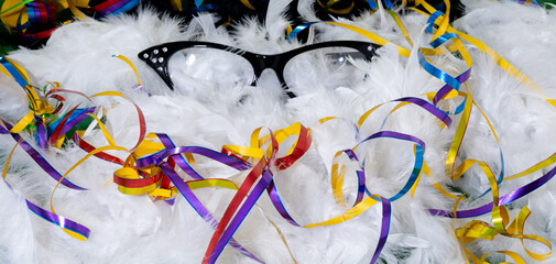 Black carnival glasses with colorful streamers on white feathers