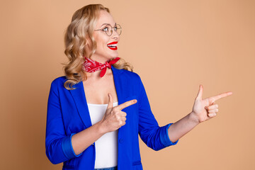 Stylish woman in blue jacket smiling and gesturing enthusiastically with a beige background