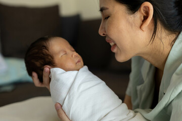 Fototapeta premium A woman is holding a baby in her arms. The baby is crying and the woman is trying to comfort it 
