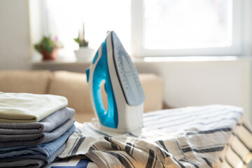Electric iron and pile of clothes on ironing board