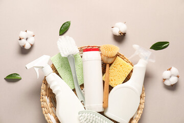 Bottles of different cleaning products, tools, cotton flowers and leaves on beige background, flat lay