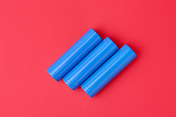 Three AA cell batteries on red background, top view
