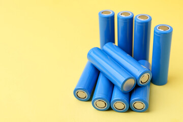 Many AA cell batteries on yellow background, closeup. Space for text