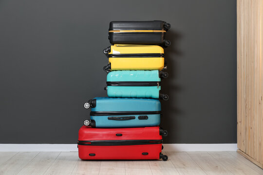 Stack of colorful suitcases on floor near black wall