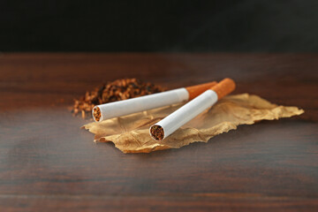 Tobacco, dried leaf and cigarettes on wooden table, closeup