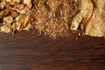 Shredded and whole dried tobacco leaves on wooden table, top view