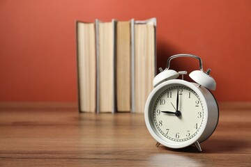 Alarm clock and books on wooden table, space for text. Time for knowledge © New Africa