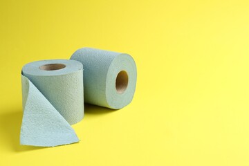 Light blue toilet paper rolls on yellow background, space for text