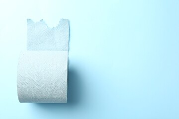 Color toilet paper roll on light blue background, top view. Space for text