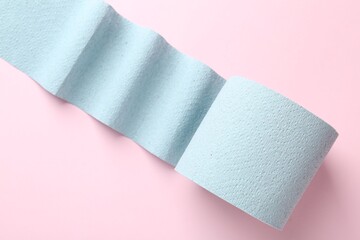 Blue toilet paper roll on light pink background, top view