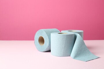 Blue toilet paper rolls on pink background. Space for text