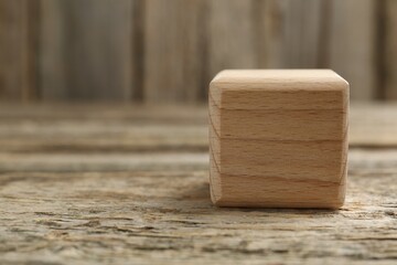 One cube on wooden table, closeup. Space for text