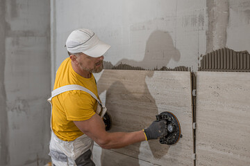 Tiling with large format tiles. A tiler placing a tile held by a tile suction cups.