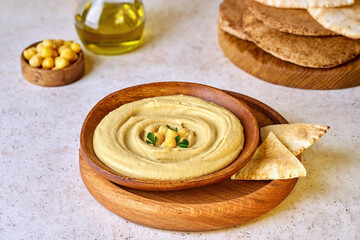 Chickpea hummus in wood plate with pita bread and paprika. Closeup view