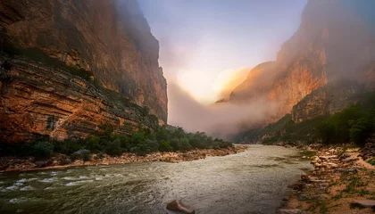 Fototapete Fog is rising from the river in a dramatic canyon at sunset © João Macedo
