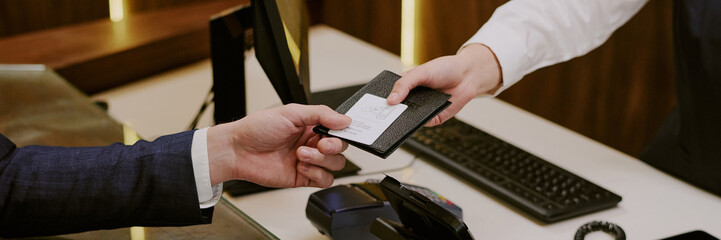 Website banner with unrecognizable delicate female hand giving back passport in black leather cover...