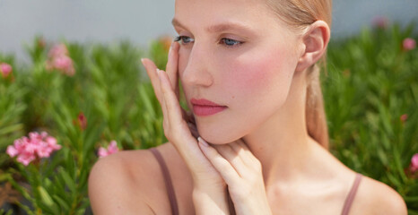Beauty serene close-up portrait a young woman gently touching her cheek, showcasing healthy and...