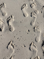 Huellas de personas en la arena blanca de una playa. 