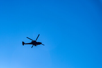 A military helicopter silhouette on a blue sky