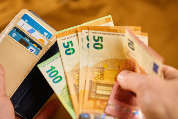 Wallet with euro banknotes and credit cards in hands. Person holding purse and taking out cash...