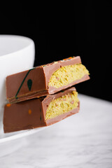 Dubai chocolate with pistachio filling on a white plate on a black background