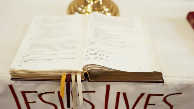 A white cloth that says Jesus Lives under The Holy Bible in a small church chapel.