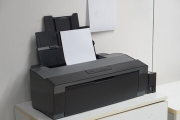 top view, old black plastic printer and white paper on white table, office background, technology,...