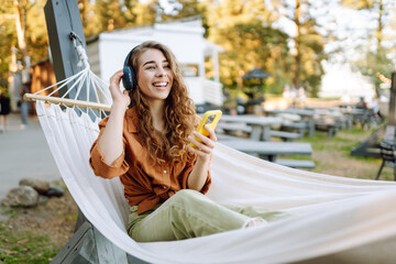 Portrait of a beautiful woman listening to music with wireless headphones and a phone. Young woman...