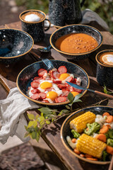 Comida cocinada en platos y sartenes de metal al exterior en un campamento de día