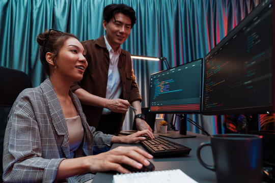 IT developers discussing with point to intelligent website development coder system running data online two screens information technology at neon light room at modern office. Infobahn.